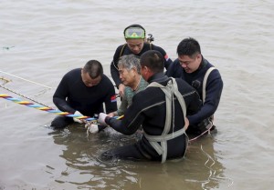 A woman is helped after being pulled out by divers from a sunken ship in Jianli