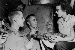 Two American soldiers , who are brothers, sample doughnuts offered by a member of an American red Cross clubmobile in Normandy