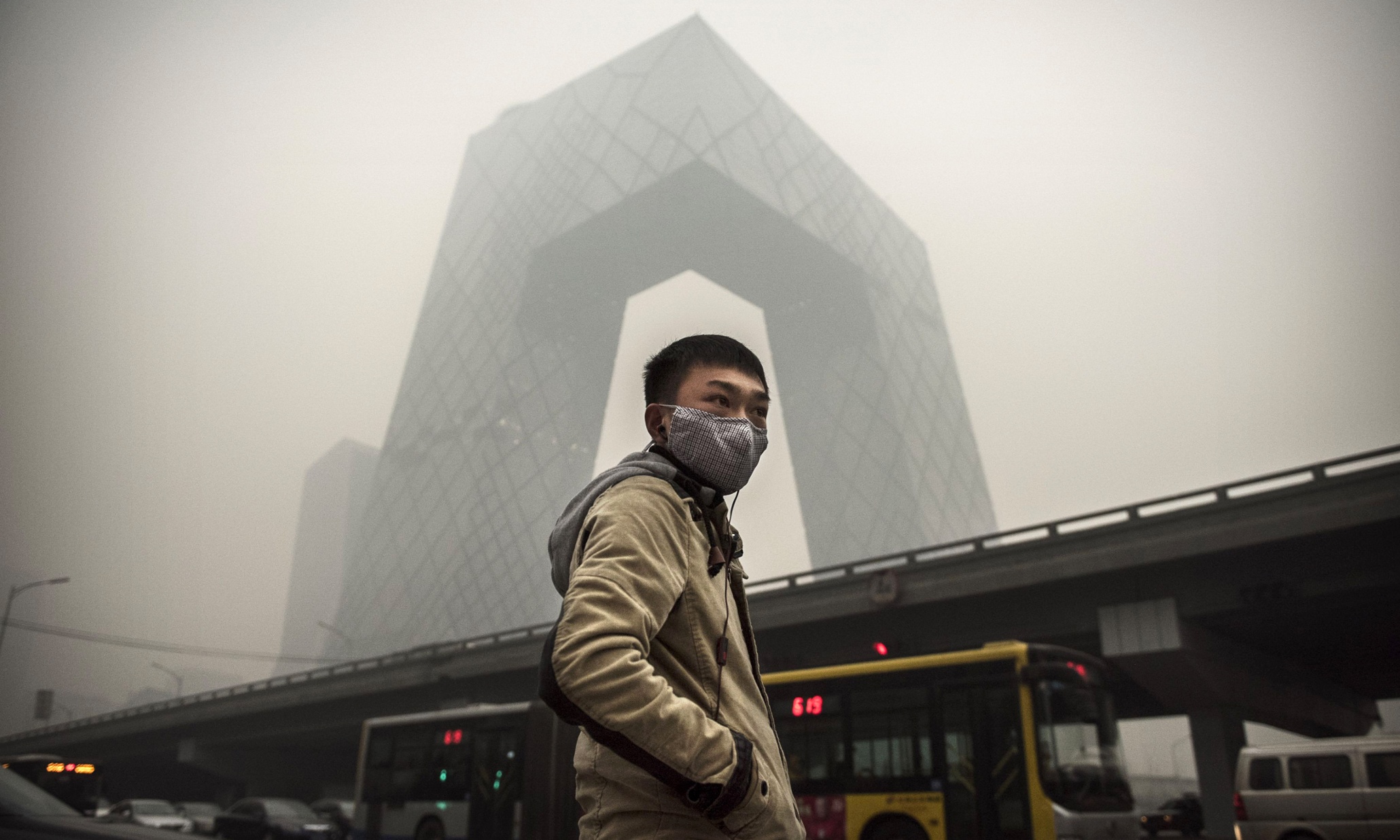 BEIJING, CHINA - NOVEMBER 29: A Chinese man wears a mask as he waits to cross the road near the CCTV building during heavy smog on November 29, 2014 in Beijing, China. United States President Barack Obama and China's president Xi Jinping agreed on a plan to limit carbon emissions by their countries, which are the world's two biggest polluters, at a summit in Beijing earlier this month. (Photo by Kevin Frayer/Getty Images) *** BESTPIX ***