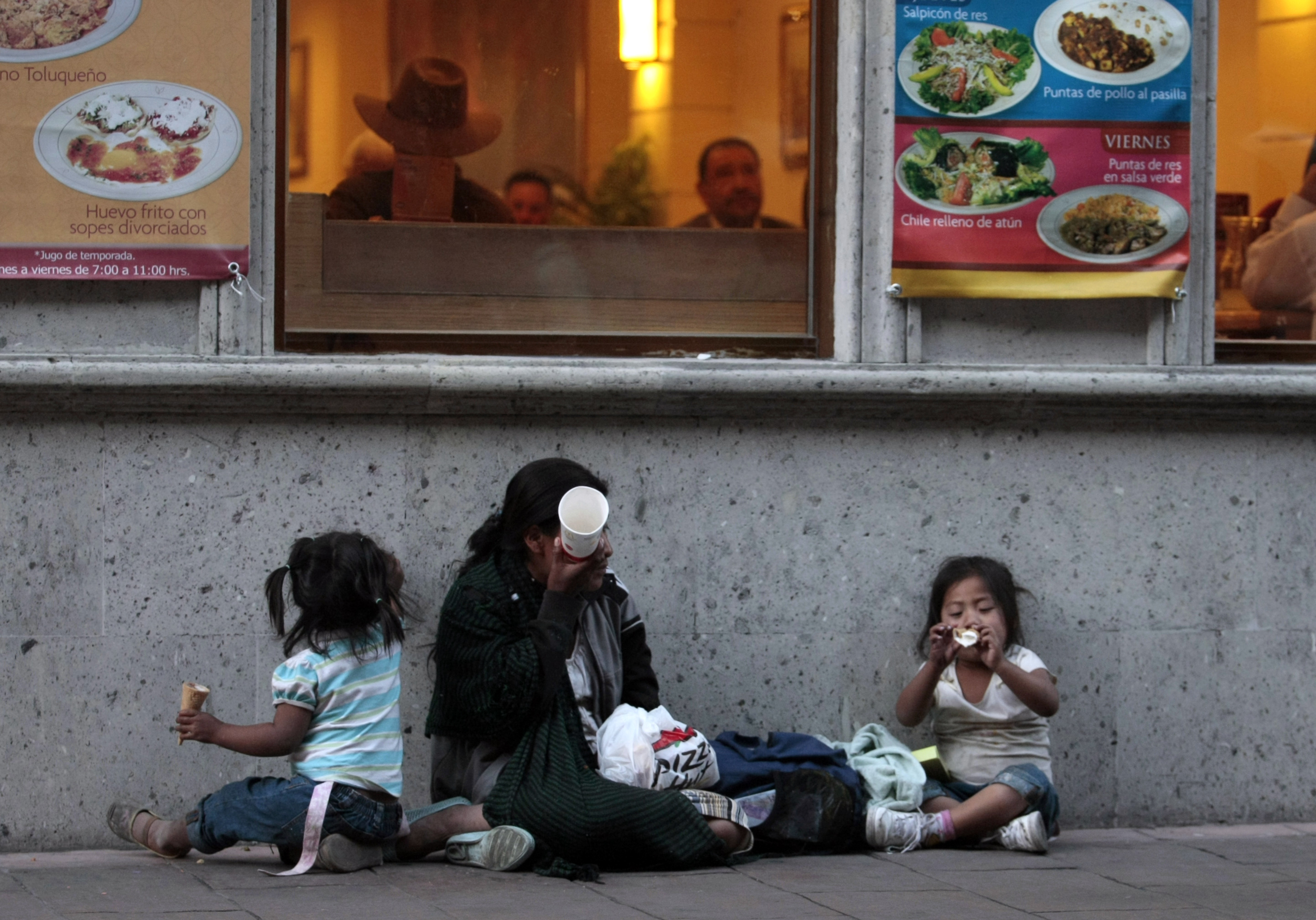 A homeless woman and her children sit outside a restaurant as she waits to receive a handout in Mexico City's historic Zocalo Square December 10, 2008. Picture taken on Dec 10. REUTERS/Henry Romero(MEXICO)