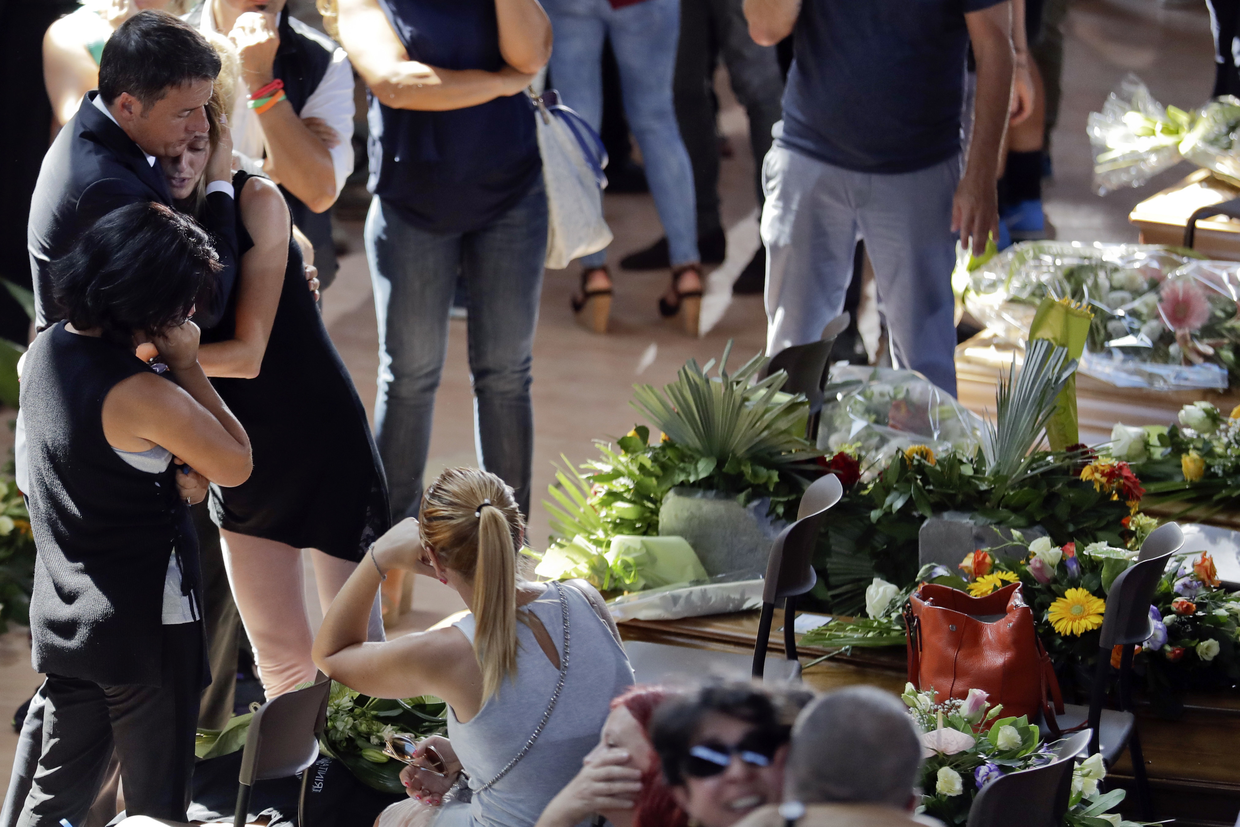 El primer ministro italiano Matteo Renzi, izquierda, conforta a una mujer al final de un funeral de estado para algunas de las víctimas del terremoto que sacudió el centro de Italia el mércoles, en Ascoli PIceno el sábado, 27 de agosto del 2016.  (AP Foto/Andrew Medichini)